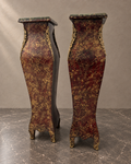 Pair of burgundy-and-gold decorative pedestals with green marble tops in a styled setting