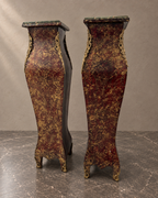 Pair of burgundy-and-gold decorative pedestals with green marble tops in a styled setting