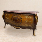 Louis XV-style chest with floral marquetry, bronze mounts and rose marble top, staged on a pale stone floor.