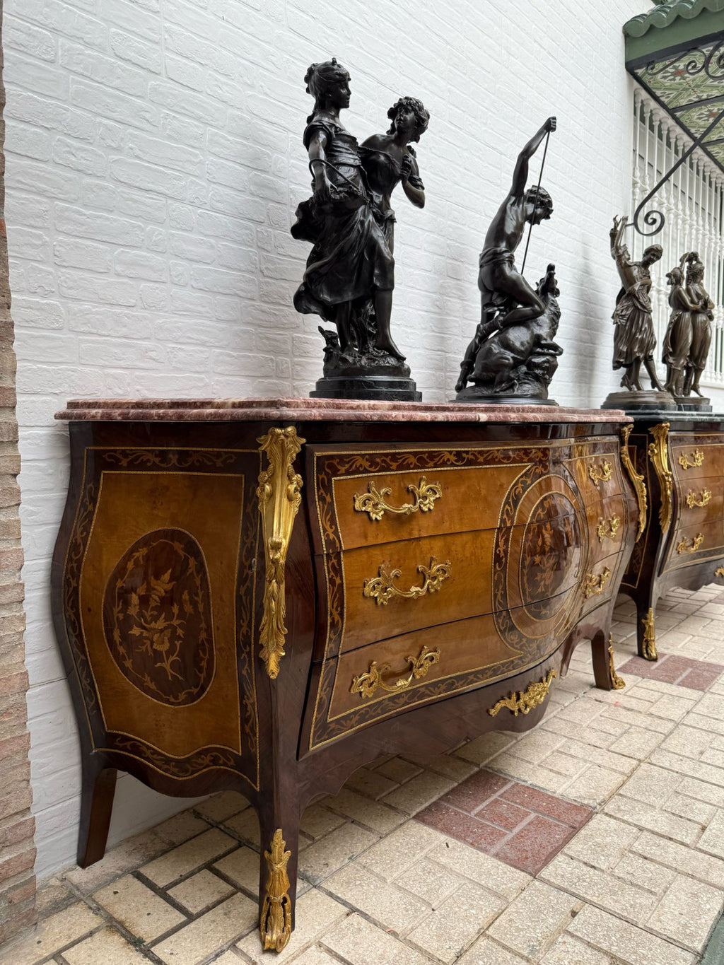 Original side view of the rose marble marquetry chest, showing its curved side panel and legs. Decorative objects are not included.